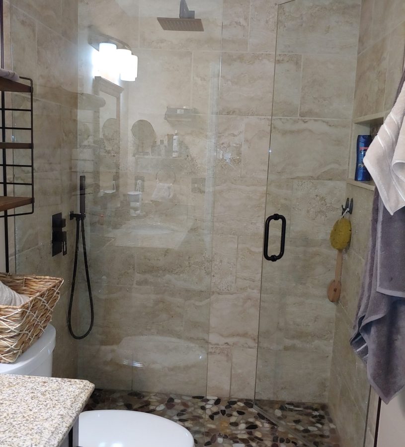 bathroom with glass door and tiled walls